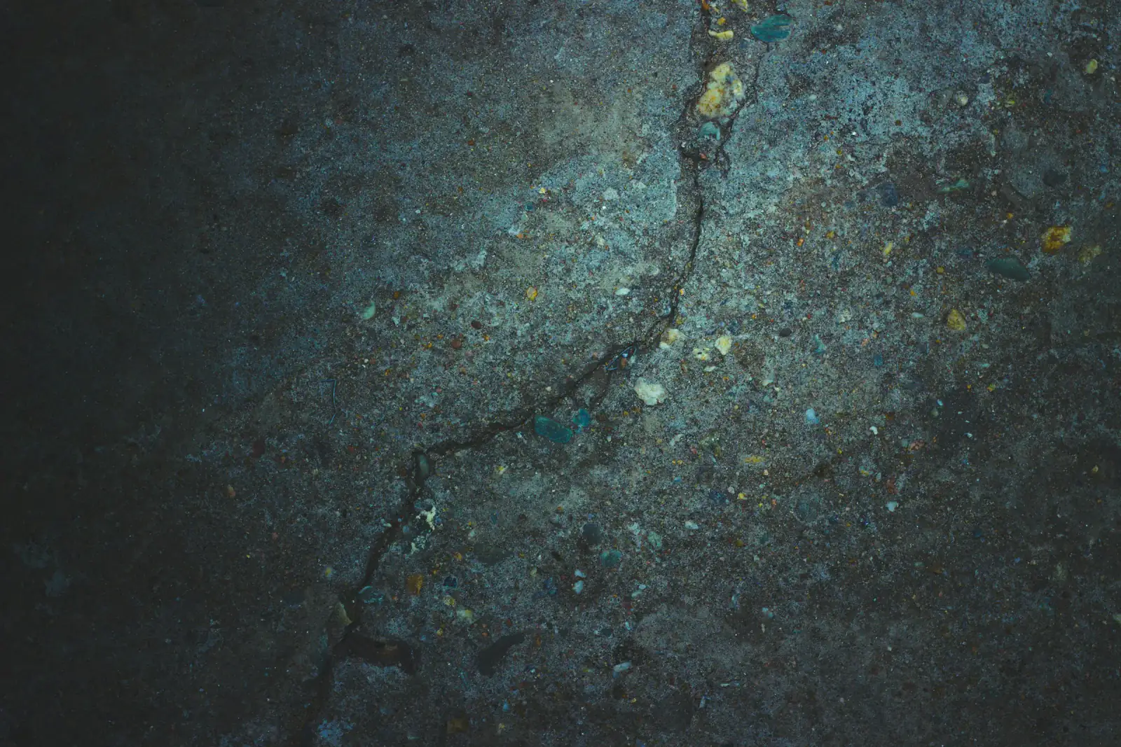 A crack running across a dark concrete slab