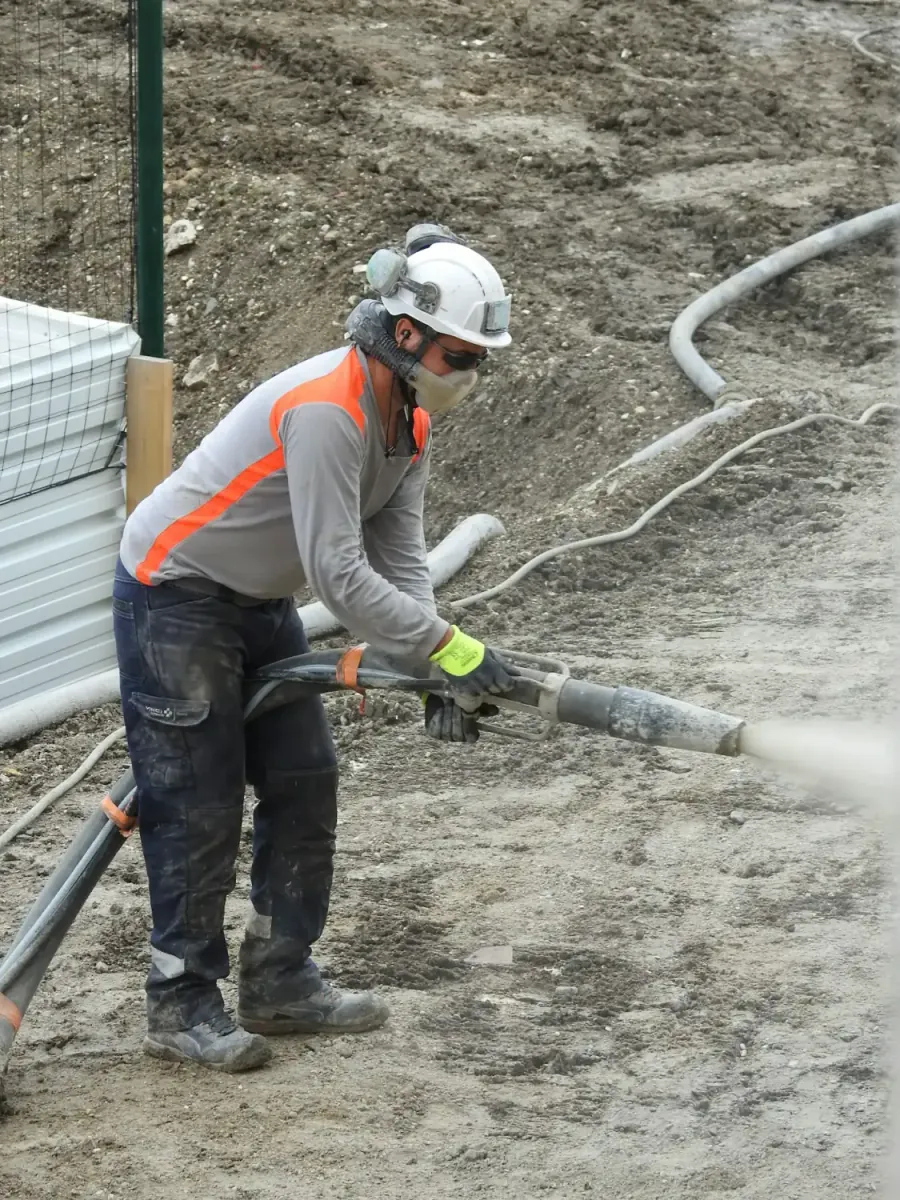 A worker in a hard hat clearing a line with a high-pressure hose