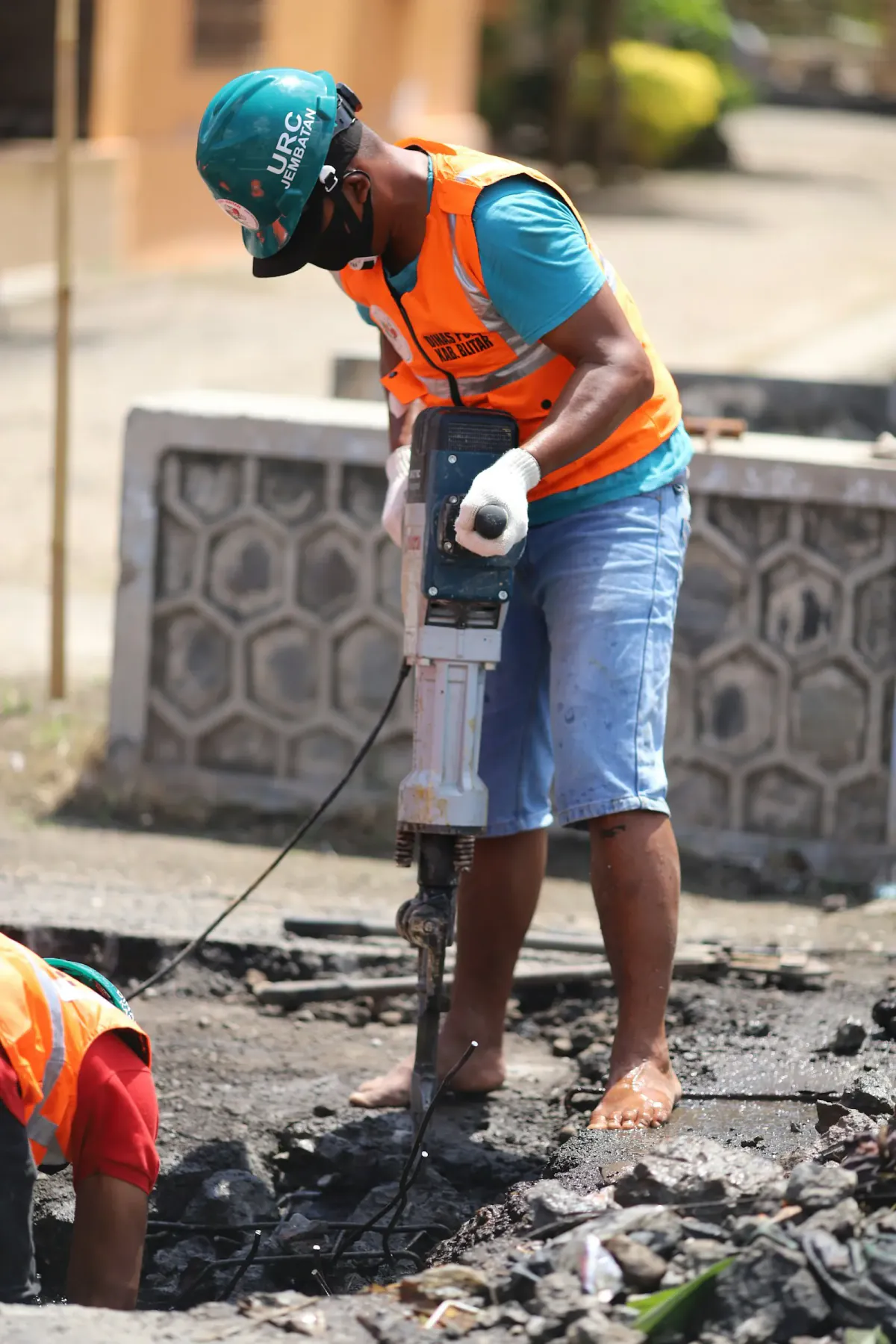 A worker breaking up concrete with a jackhammer